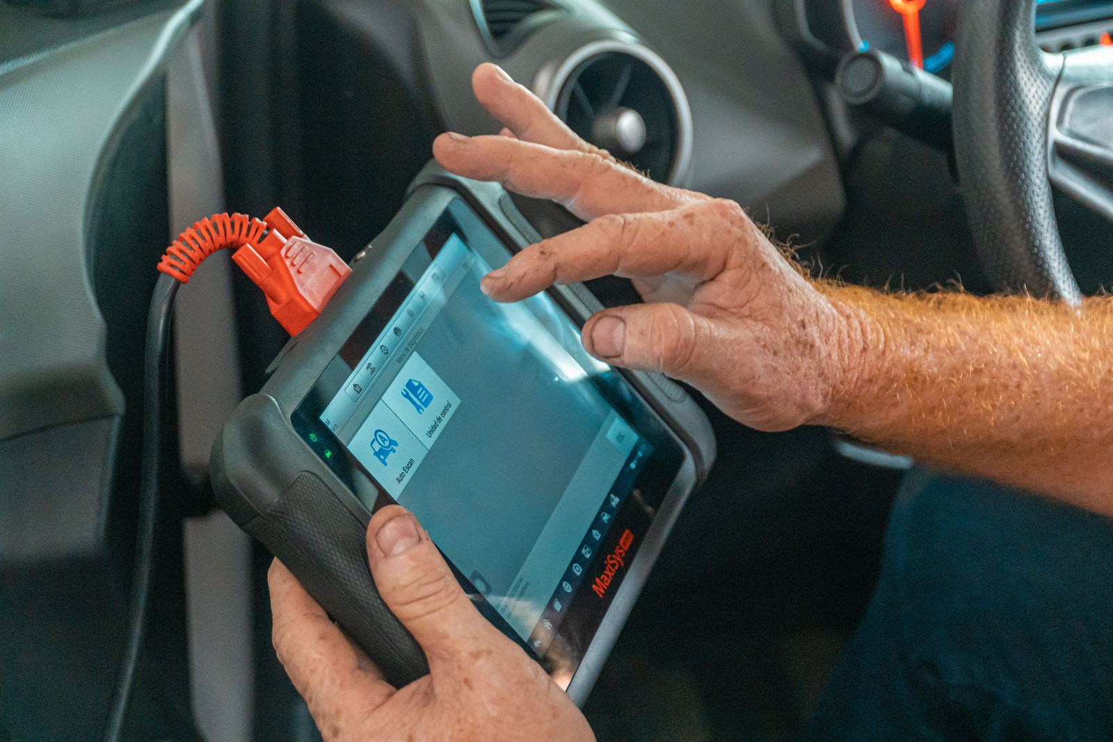 A handheld diagnostic tablet connected to a vehicle, showing a scan in progress.